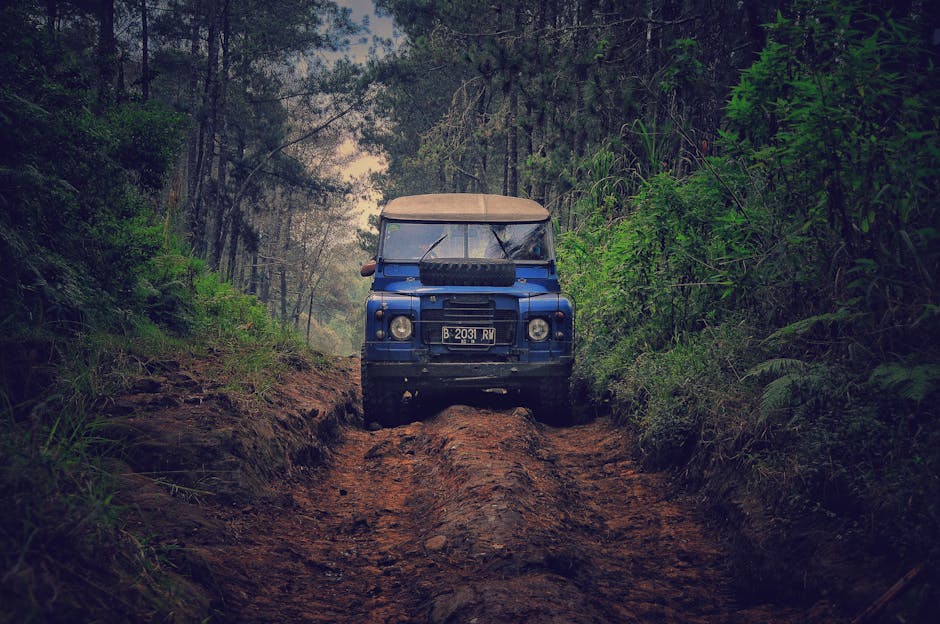 Off-road vehicle traversing a rugged dirt path through lush forest in Parongpong, Indonesia