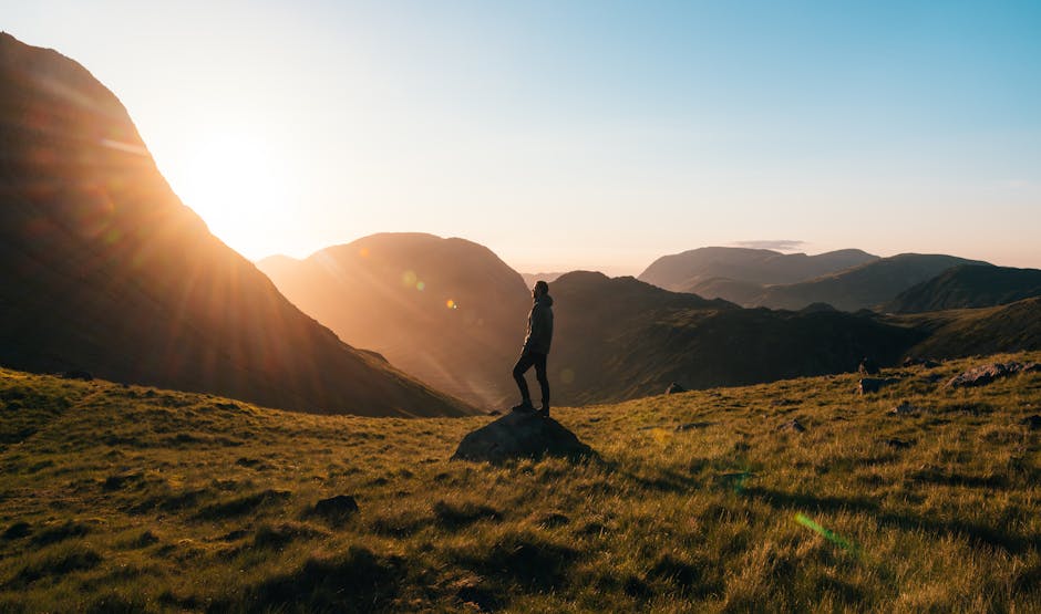 Silhouette of a person standing on a hill during sunrise in Cumbria, England with scenic mountain views