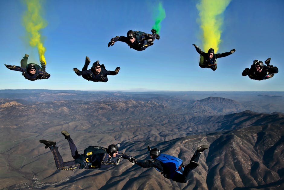 Dynamic aerial shot of skydivers performing stunts with colorful smoke trails over mountainous terrain